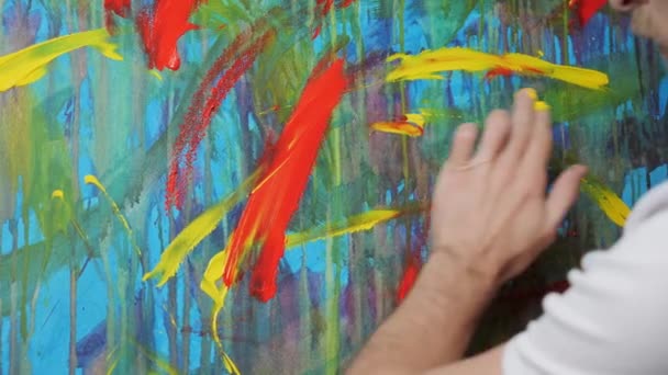 Gros plan sur les peintures à la main de l'artiste masculin avec ses doigts une image sur toile. — Video