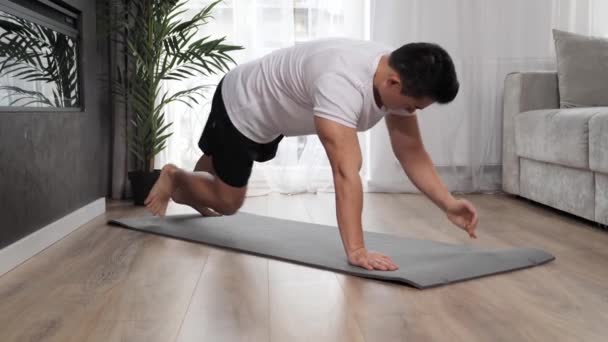 Snygg asiatisk kille tränar hemma gör sport övningar. — Stockvideo