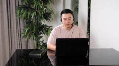 Zeki Asyalı adam laptopta konferans görüntülü konuşma yapıyor..