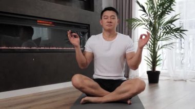 Güçlü genç Asyalı adam evde yoga yapıyor. Sağlıklı yaşam tarzı kavramı..