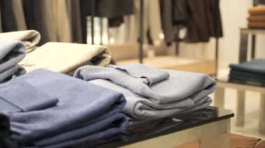 Bir adam elbise ile askıya yaklaşır ve mavi bir kazak alır. Noel indirimi.