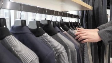 Erkeklerin elleri şık erkek kıyafetleri satan bir mağazadan ceket askısı alır..