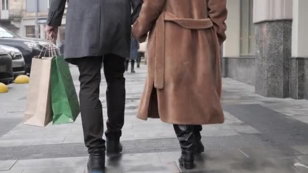 一个男人和一个女人提着购物袋在街上走着. — 图库视频影像