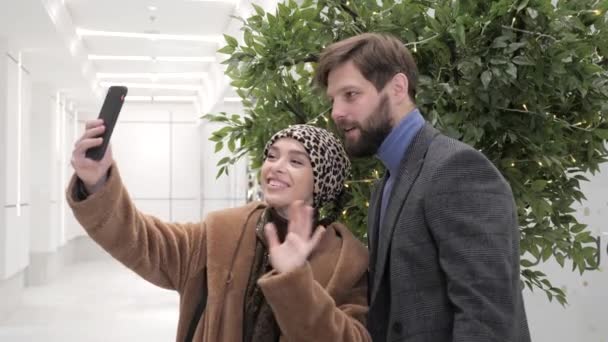 Жена и муж делают видеозвонок, стоя в торговом центре на распродаже мешков. — стоковое видео