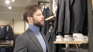 Genç adam, alışveriş merkezindeki şık erkek giyim mağazasında ceket ölçer.. 