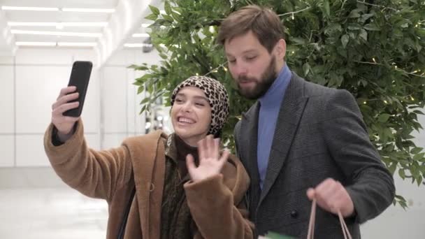 Feliz pareja casada teniendo videollamada en un centro comercial sosteniendo bolsas de compras. — Vídeos de Stock