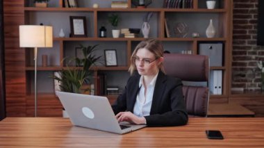 Mutlu gülümseyen genç iş kadını çalışma masasında oturarak bilgisayarını esnetmeyi bitirdi. Mutlu, rahat iş kadını stres attığını hissediyor. İyi iş çıkardın. Bilgisayarı kapat..