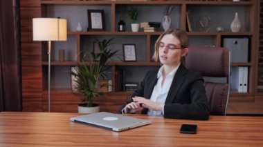 Gülümseyen, kendine güvenen iş kadını bilgisayar işini bitirdi, dizüstü bilgisayarı kapattı. Gözlüklerini çıkardı. Stres atma, proje başarısından tatmin oldu..