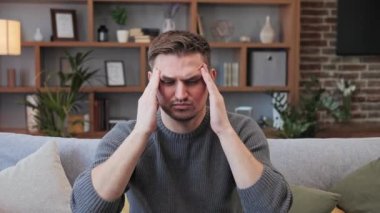 Kafkasyalı yorgun ofis çalışanı baş ağrısı çeken serbest çalışan patronun portresi. Stresli bir adam günlük kıyafetlerle acı çekiyor ve baş masajı yapıyor. Rahatlamak ve kapalı alandaki ağrıyı azaltmak için..