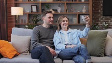 Neşeli genç erkek arkadaş ve kız arkadaş el sallıyor ve internet video konferansı aracılığıyla iletişim kuruyor. Evde oturan arkadaşları ya da ailesi ile çevrimiçi video görüşmesi yapıyorlar. Uzaklık iletişimi video çağrısı.