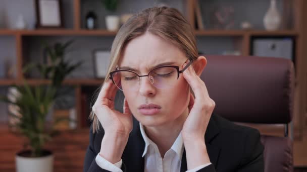 Stressad ung kvinna i glasögon som lider av muskelspänningar, har smärtsamma huvudkänslor på grund av datoröverarbete eller stillasittande arbetsliv. Trött anställd överväldigad av uppgifter i ämbetet. — Stockvideo
