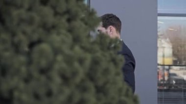 Başarılı bir iş adamının portresi şık bir takım elbise giyiyor ve ofis binalarının yakınında dokümanlarla dolanıyor. Akıllı telefonu olan bir adam mesaj yazıyor. İş konsepti. Yan görünüm.