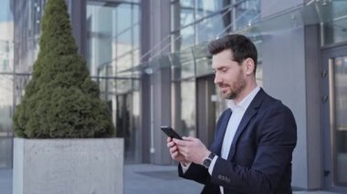 Düşünceli bir iş adamı büyük modern iş bölgesinin yanındaki bankta oturuyor. Genç sakallı bir adam Smartphone 'da mesajlar yolluyor. Kaydırıyor, daktilo çekiyor, interneti tarıyor, sosyal medyada gülümsüyor..