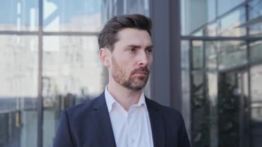 Kameraya bakan odaklanmış sakallı, bin yıllık profesyonel iş adamı. Mutlu, kendine güvenen, zeki, genç, yetişkin girişimci, lider, yönetici ofisin dışında poz veriyor. Yüz görünümü iş portresi.