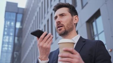 Gülümseyen İşadamı hoparlörden ses tanıma mesajı kaydediyor. Sanal asistan uygulaması kullanan işadamı ofis bölgesindeki dijital mobil yardım teknolojisi konseptinde akıllı telefonda anımsatıcı ayarladı