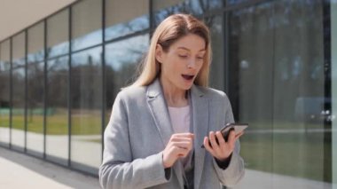 Heyecanlı yetişkin kadın akıllı telefonundaki mesajla seviniyor. Cep telefonuna bakan mutlu iş kadını zaferi kutluyor. Şanslı kumarbazın portresi evet diyor..