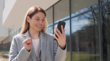 Güzel Mutlu Genç Kadın Finansal Bölgede Çevrimiçi Video Arama Yürüyüşü için Akıllı Telefon Kullanıyor. Gülümseyen Kadın Cep Telefonu Kullanıyor Aile Arkadaşlarıyla ya da İş Arkadaşlarıyla Sohbet Ediyor.