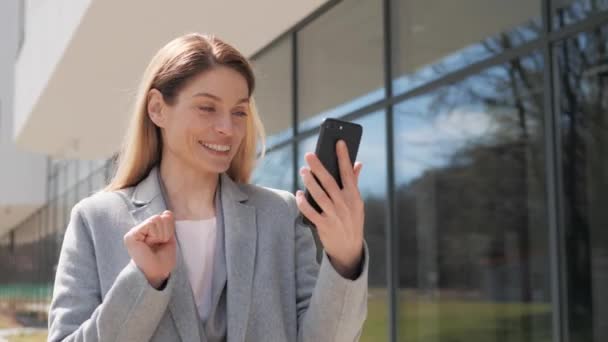 Belle jeune femme heureuse utilisant Smartphone pour la marche d'appel vidéo en ligne dans le quartier financier. Portrait Femme souriante utilisant un téléphone portable bavarder avec des amis de la famille ou des partenaires d'affaires à l'extérieur. — Video