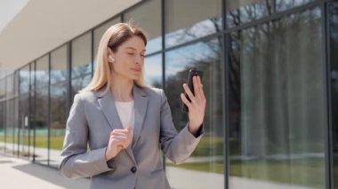 Orta yaşlı beyaz bir iş kadınının portresi. Elinde cep telefonuyla şık bir görünüşü var. İş ortağıyla görüntülü konuşma yapıyor. Kadın milenyum CEO 'su sohbetten hoşlanıyor.