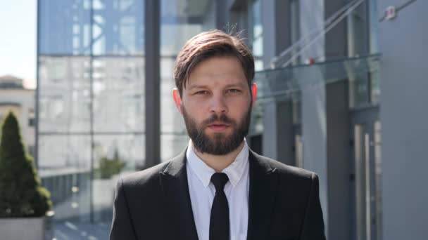 Face portrait of successful businessman looking serious to camera stands outdoors near modern city business building bearded male model attractive entrepreneur in formal suit posing Business portrait. — стоковое видео