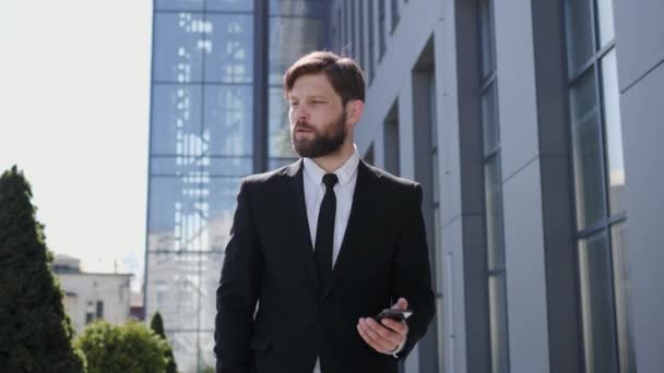 Handsome Young Bearded Businessman or Manager is using his Smartphone Looking Focused. Hipster Businessman is texting Messages Reading Sms while surfing the Internet. Successful Business People. — ストック動画