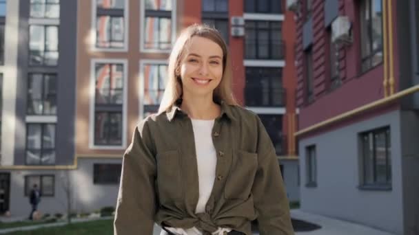 Mulher feliz bonito andando na rua urbana transformando o cabelo voador olhando para a câmera. Retrato de menina rindo bonita com dentes brancos saudáveis. Senhora sorridente sexy. Emoção positiva. Bom humor.. — Vídeo de Stock