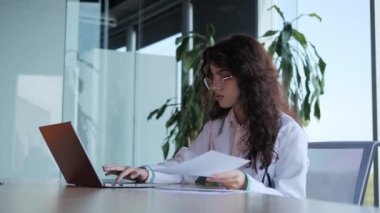 Laboratuar önlüklü güzel kıvırcık saçlı kadın doktor ve dizüstü bilgisayarında mesaj yazan gözlüklü, hastalığın sonucunu okuyan doktor, tıp bürosunda çalışırken bilgisayara girdi..