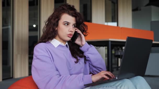 Έξυπνη δημιουργική γυναίκα φορώντας casual ρούχα και γυαλιά που εργάζονται με φορητό υπολογιστή στο γραφείο απαντώντας πελάτη κλήση μιλάμε κινητό τηλέφωνο με το διευθυντή πωλήσεων πελατών παίρνει παραγγελία online υποστήριξη αγορών. — Αρχείο Βίντεο