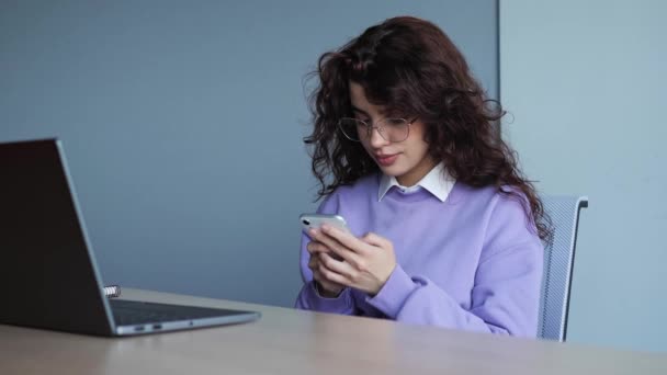 Smiling happy girl agent lawyer manager sitting at her workplace using mobile phone communication with colleagues or friends. Female worker typing message on smartphone, browsing internet indoor. — Wideo stockowe