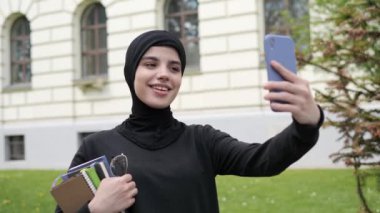 Kadın portresi İslami güzel kız genç müslüman kadın arkadaş canlısı tesettürlü bayan öğrenci tesettürlü sohbet eden online cep telefonu sohbet konferansı videosu açık havada..