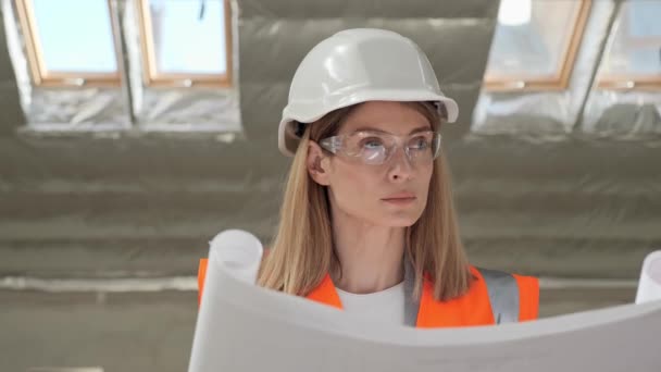 Portrait of thoughtful talented pretty female architect analyzing blueprint in modern building standing at window. Busy concentrated adult woman looking at architectural plan thinking. Talent concept. — Αρχείο Βίντεο