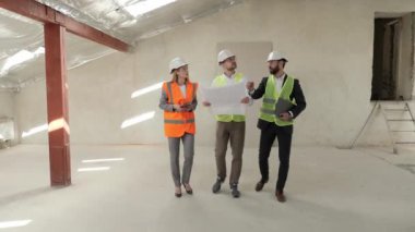 Üç kişiden oluşan bir grup. İki işadamı ve mimar mühendisi güvenlik kaskı taktıkları inşaat alanının planını inceliyor ve tartışıyorlar. Yatırımcı ve İşçi Endüstri Binasını Tamamladı.