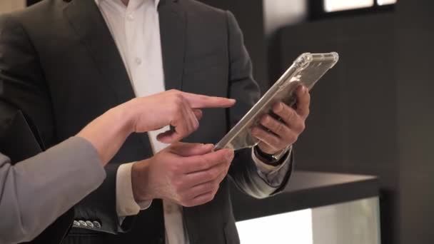 Vue rapprochée mains d'homme d'affaires avec tablette dans la salle de bureau. Partenaires commerciaux hautement qualifiés examinant le projet de démarrage sur un appareil numérique moderne pendant la réunion. Femme pointant du doigt à l'écran du gadget. — Video