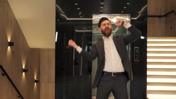 Funny excited businessman celebrating victory, dancing in modern hall office. Male person having fun enjoy job opportunities. Career people. Celebration. Man Celebrates Successful Project New Job. — Stockvideo