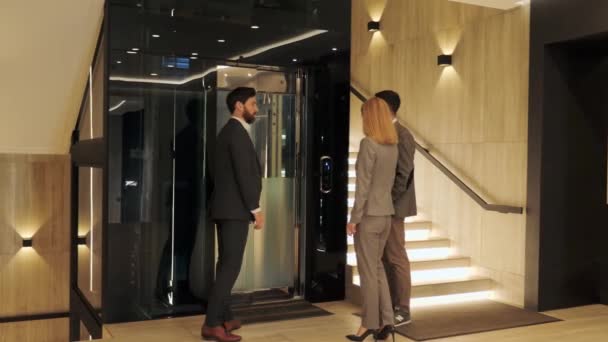 Un grupo de empresarios entra en un moderno ascensor y discute la reunión corporativa en el centro de negocios. Se levanta delegación internacional de expertos en servicios jurídicos. La puerta se cierra. Escaleras de iluminación. — Vídeo de stock