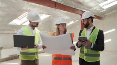 Uzmanlardan oluşan bir ekip inşaat sahasında dizüstü bilgisayar tableti planları kullanıyor. İnşaat Mühendisi, Mimar, İş Yatırımcısı ve Genel İşçi Planlama Ayrıntıları ile Emlak Boş Bina Projesi.