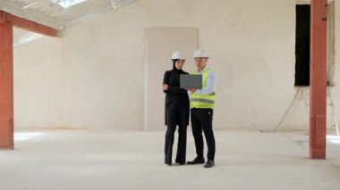 İki farklı çok uluslu profesyonel insan. Güvenlik Üniforması Giyen Asya Endüstri Mühendisi. Dizüstü bilgisayarda Arap Müslüman Yatırımcıyla Konuşan Proje 'yi gösteriyor. Yatırım Anlaşması Tartışılıyor