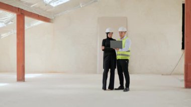 Çeşitli Çok Uluslu İş Adamları. Güvenlik Üniforması Giyen Asya Endüstri Mühendisi. Dizüstü bilgisayarda Arap Müslüman Yatırımcıyla Konuşan Proje 'yi gösteriyor. Yatırım Anlaşması Tartışılıyor