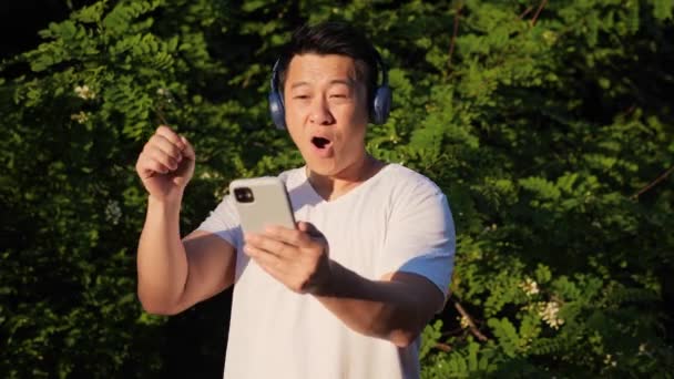 심장외과 선수로 활동하는 중국계 선수가 헤드폰을 핸드폰을 음악을 스포트만 활동적 — 비디오