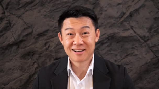 Ein Asiatischer Geschäftsmann Anzug Schaut Die Kamera Und Winkt Seinem — Stockvideo