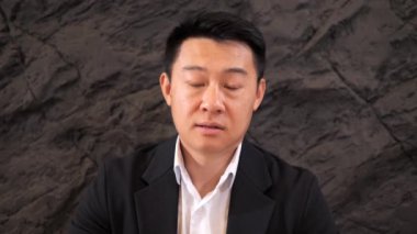 Takım elbiseli Asyalı iş adamı kameraya bakıp iş ortağıyla el sallarken çevrimiçi bağlantı konferansına katılıyor. Uzaktan iletişim videosu. Web kamerası görünümü