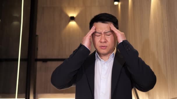 Närbild Bekymrad Koreansk Affärsman Som Har Huvudvärk Stående Trappan Inomhus — Stockvideo