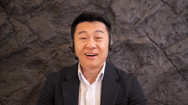 Takım Elbiseli Olumlu Odaklı Asyalı Adamı Ortağıyla Konuşurken Kameraya Bak — Stok video