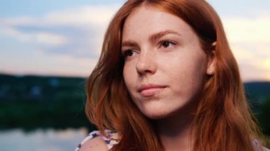 Yüzün Portresi İnanılmaz Güzel Kızıl Saçlı Genç Kız Gün Batımında Doğanın Arkasında Poz Veriyor. Doğal Çocuk Güzelliği. Kadının uzun kızıl saçı var, çilli. Kahverengi gözlü. Dışarıdaki Kadın