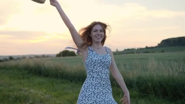 红头发快乐的小女孩 穿着夏装 夕阳西下戴着草帽跳舞 美丽的姜汁女人在户外尽情地跳着欣赏大自然 美丽的风景 — 图库视频影像