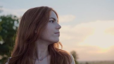 Doğada çilli güzel yüzün portresi. Kızıl saçlı, güzel çocuk yüzlü, kızıl saçlı güzel bir kadın. Gün batımında tarlada dikilen kahverengi gözlü çekici kız.