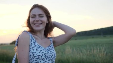 Sevimli, neşeli, mutlu, çilli, yaz elbisesi giymiş gün batımında dans eden kızıl saçlı kız. Güzel kızıl kadın doğanın tadını çıkartıyor. Güzel manzara, yaz. Özgürlük
