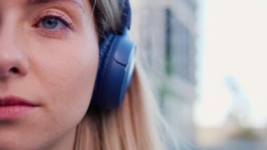 Yarım yüzü kapat, ses kopyalama alanı. Açık havada kulaklıkla müzik dinleyen mavi gözlü çekici sarışın kadın. Kulaklık takmış güzel bir kızın portresi.