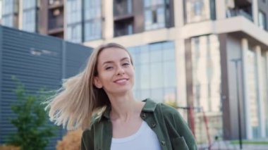 Güzel sarışın kız kameraya döndü ve el hareketleriyle beni takip etti. Çekici şehir kadını, büyüleyici gülüşü olan yaz gününün tadını çıkaran. Dışarıda güzel bir model var.