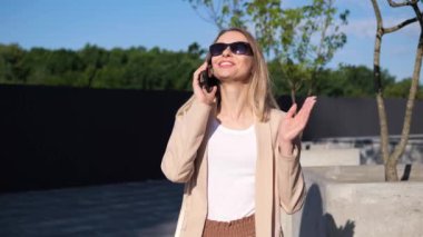 Park 'ın dışında, cep telefonuyla konuşan kendinden emin bir genç kadın. Karizmatik kız, arkadaş ya da aileyle dostça bir görüşme yapıyor. Konuşma sırasında el hareketleriyle hareket ediyor.